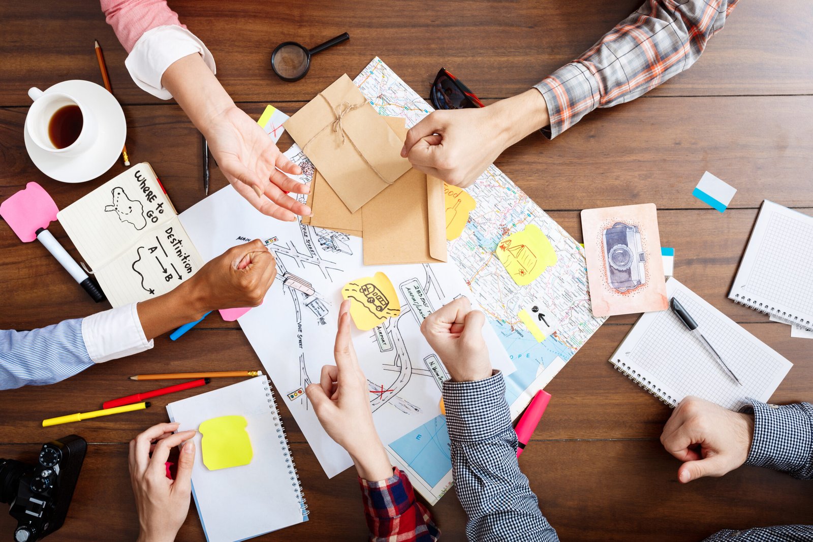 Picture of businessmen’s hands on wooden table with documents and drafts